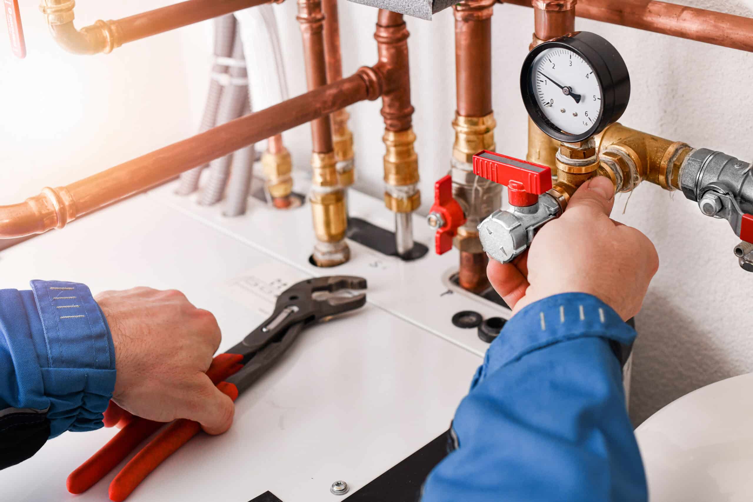 Plumber repairing residential gas piping system with pressure gauge