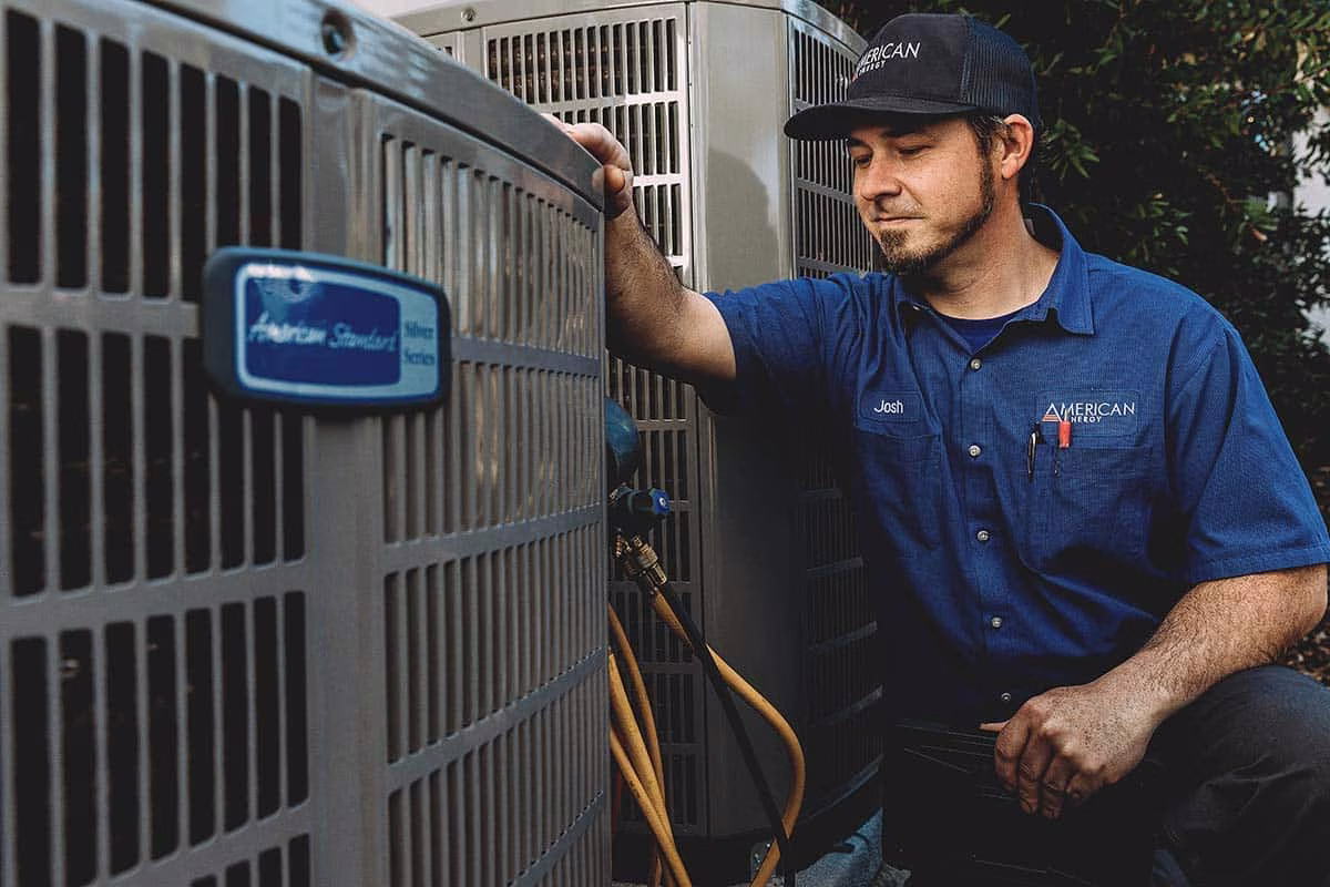 Technician performing an air conditioner tune up on an outdoor condenser unit