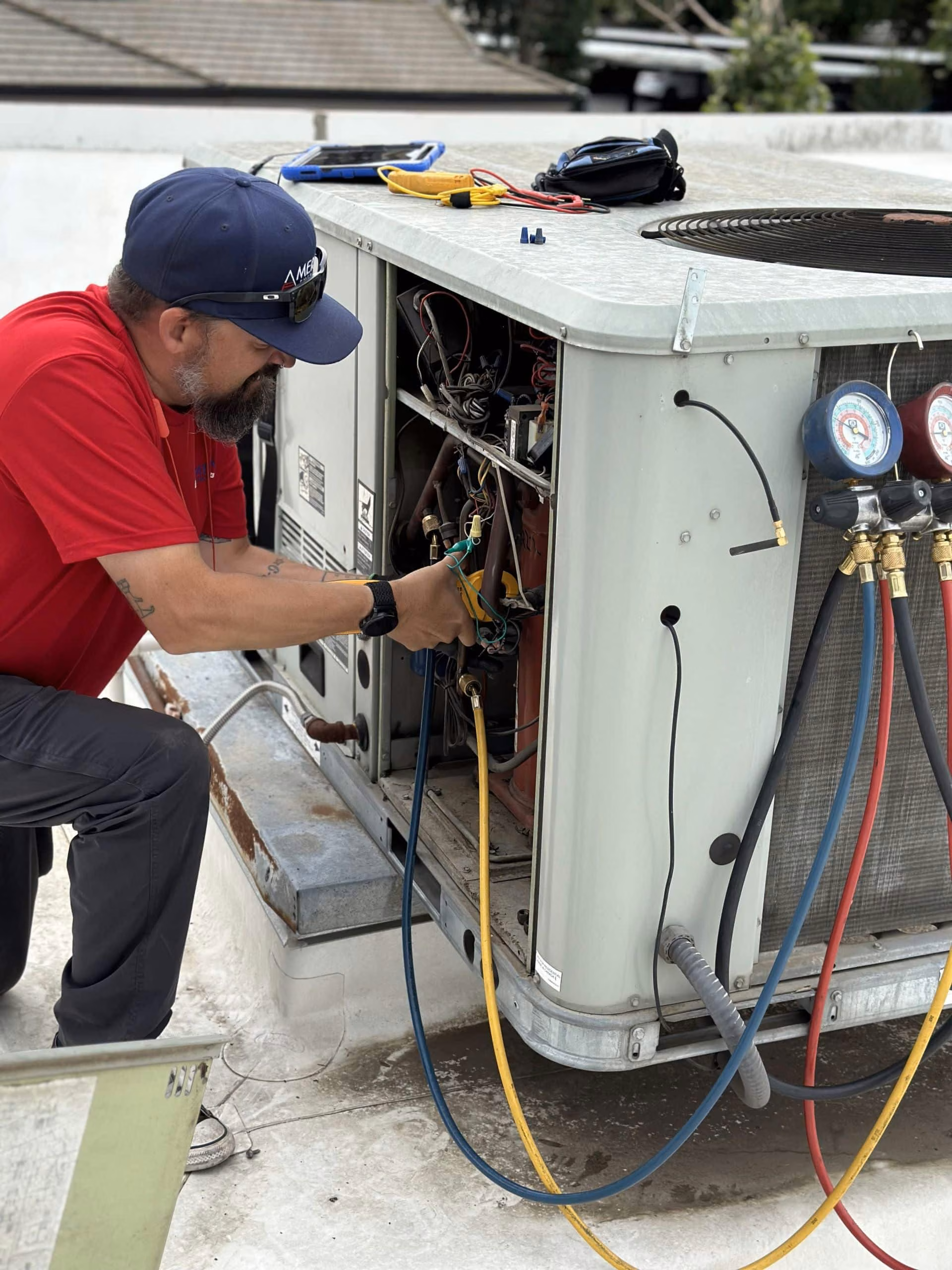 Two technicians servicing a commercial air conditioning unit with manifold gauges
