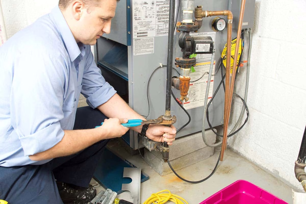 Technician using pliers on a furnace gas valve during a repair