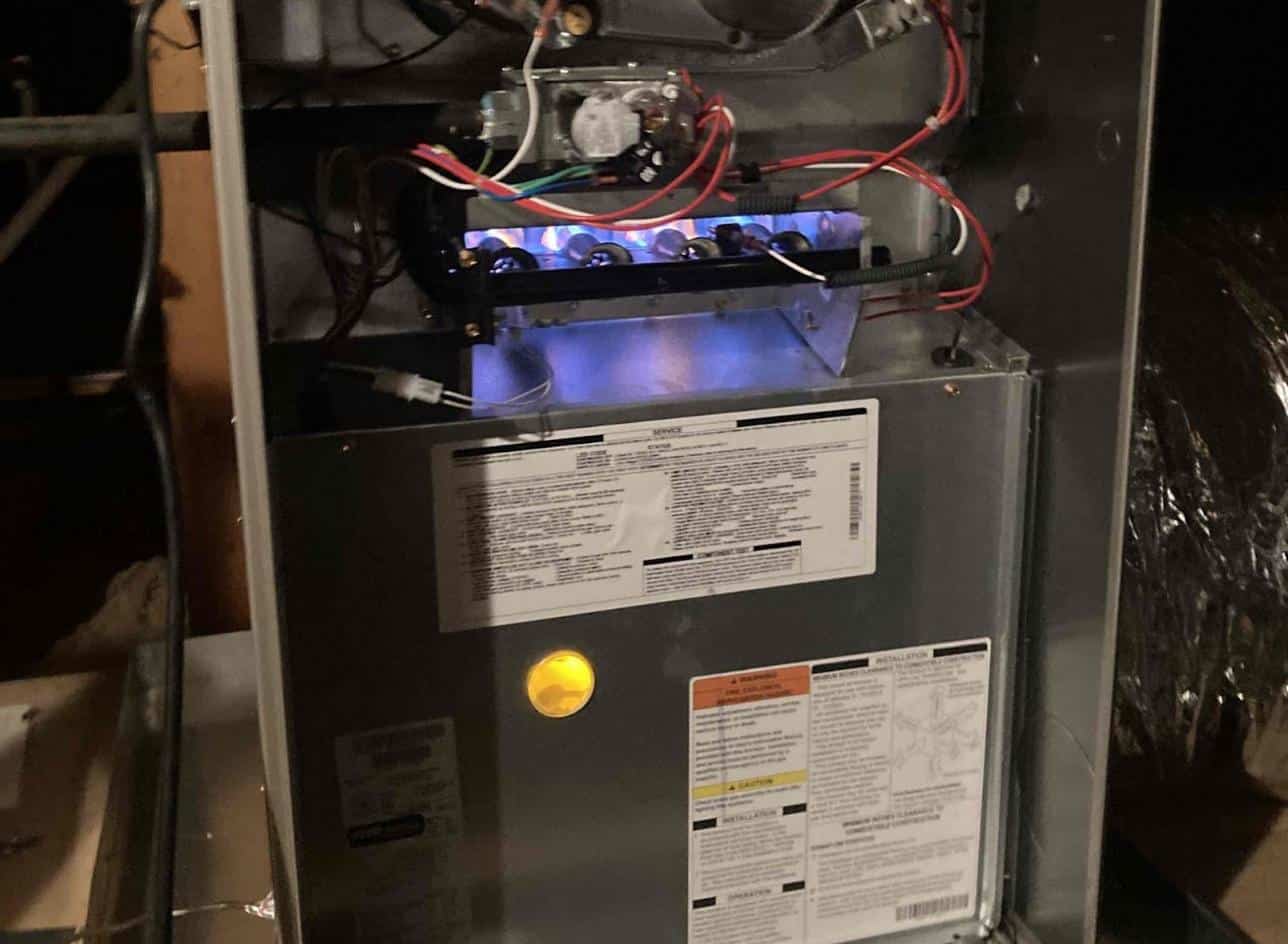 Gas furnace with burners lit during a heating repair visit