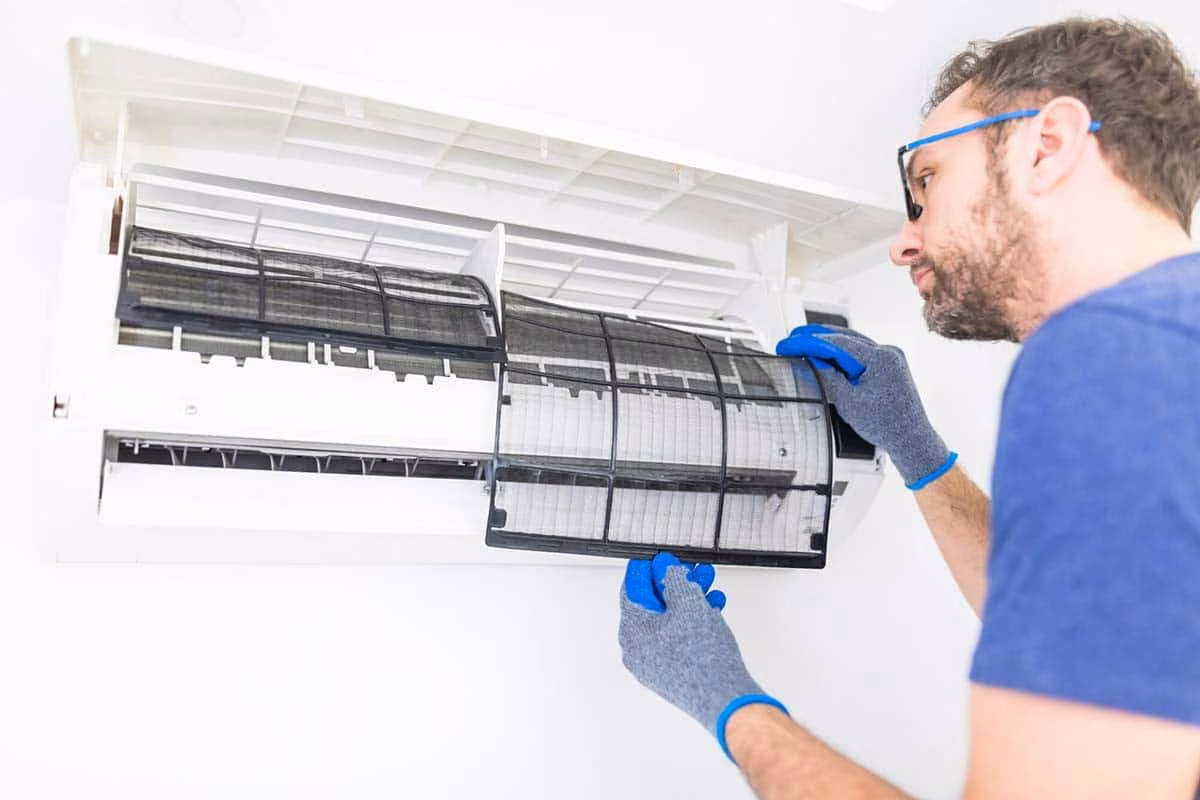 Man in gloves cleaning the filter of a wall mounted mini split unit