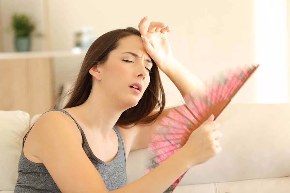 Woman fanning herself on a couch during a summer heat wave